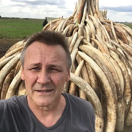Portrait of Peter Knights in front of a stacked pile of confiscated elephant tusks