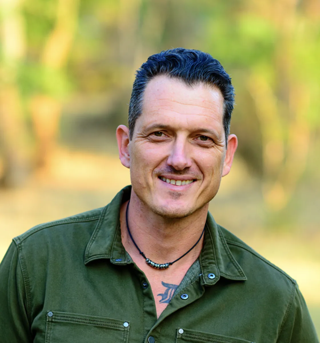 Portrait of Damien Mander in a green shirt with a forest backdrop