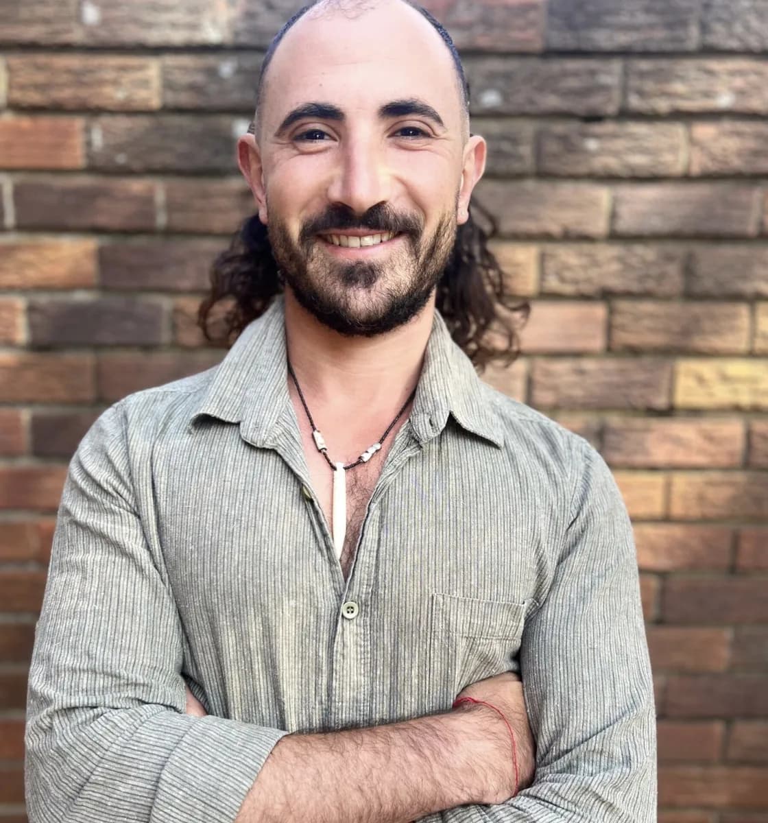 Portrait of Phivo Artemides with arms crossed against a brick wall