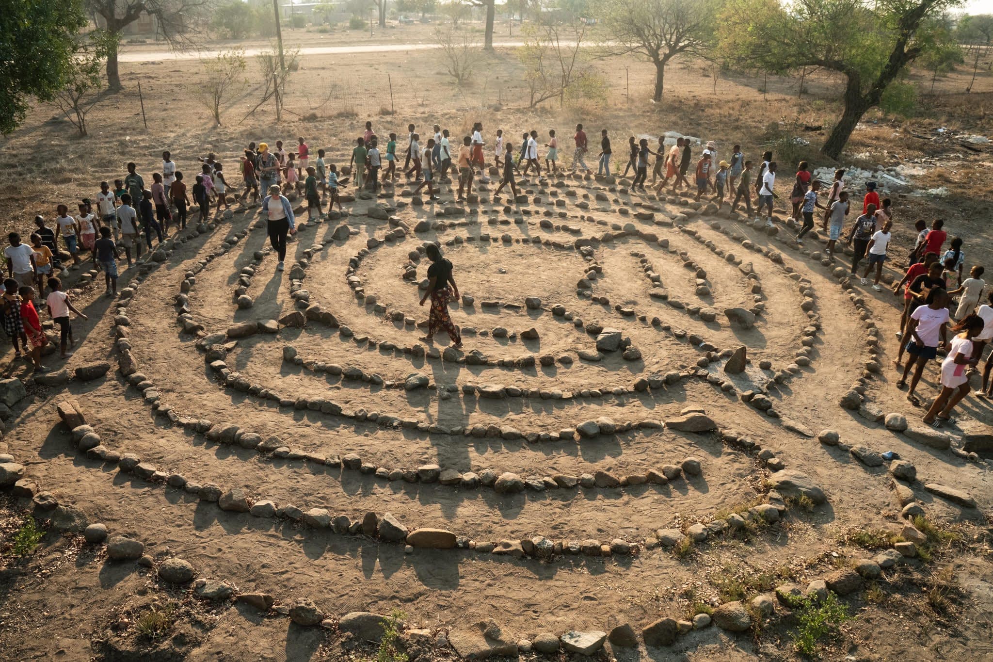 A village community gathered in a ring around a stone labyrinth