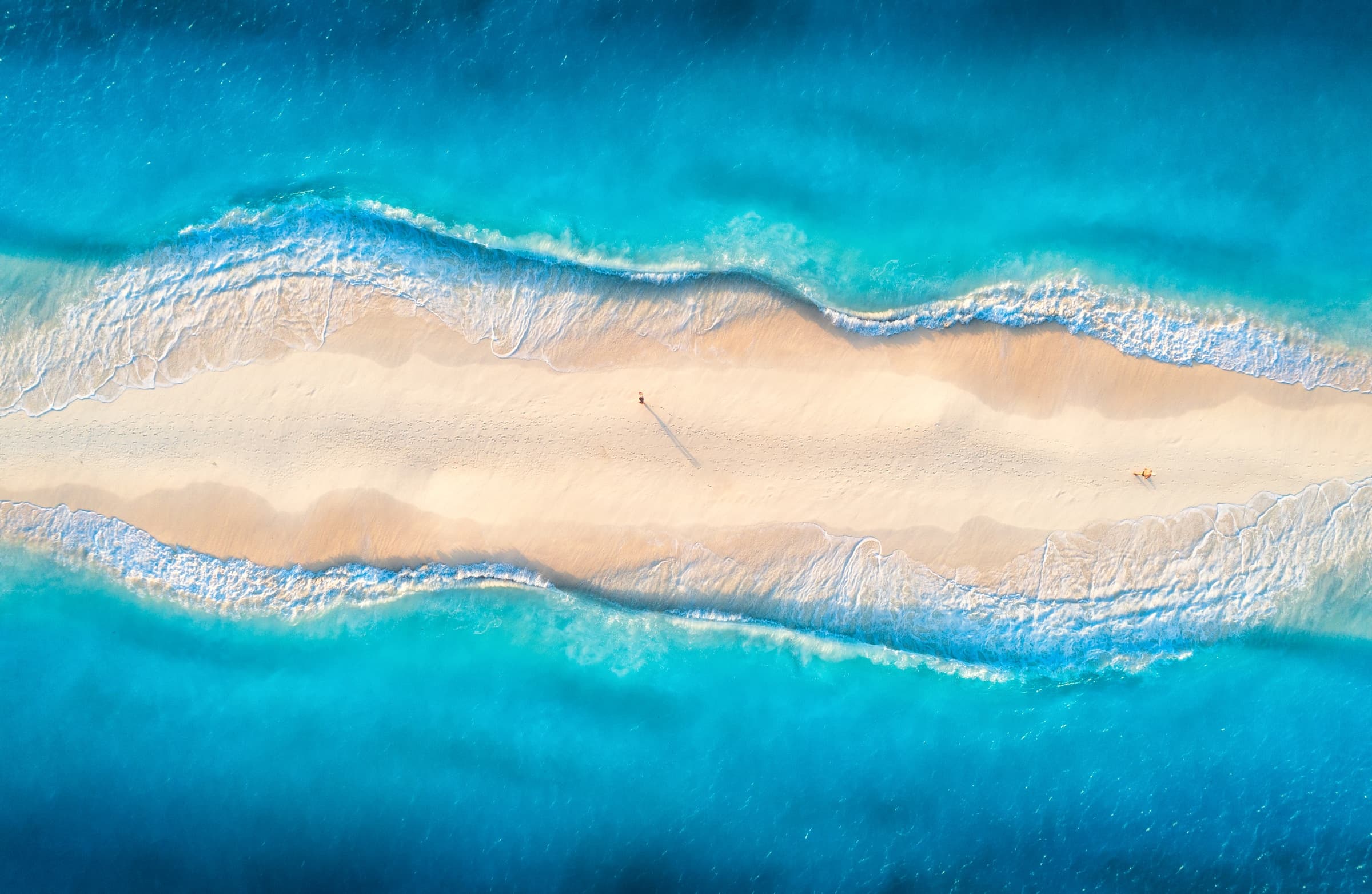 Aerial view of turquoise waves breaking on a sandbar