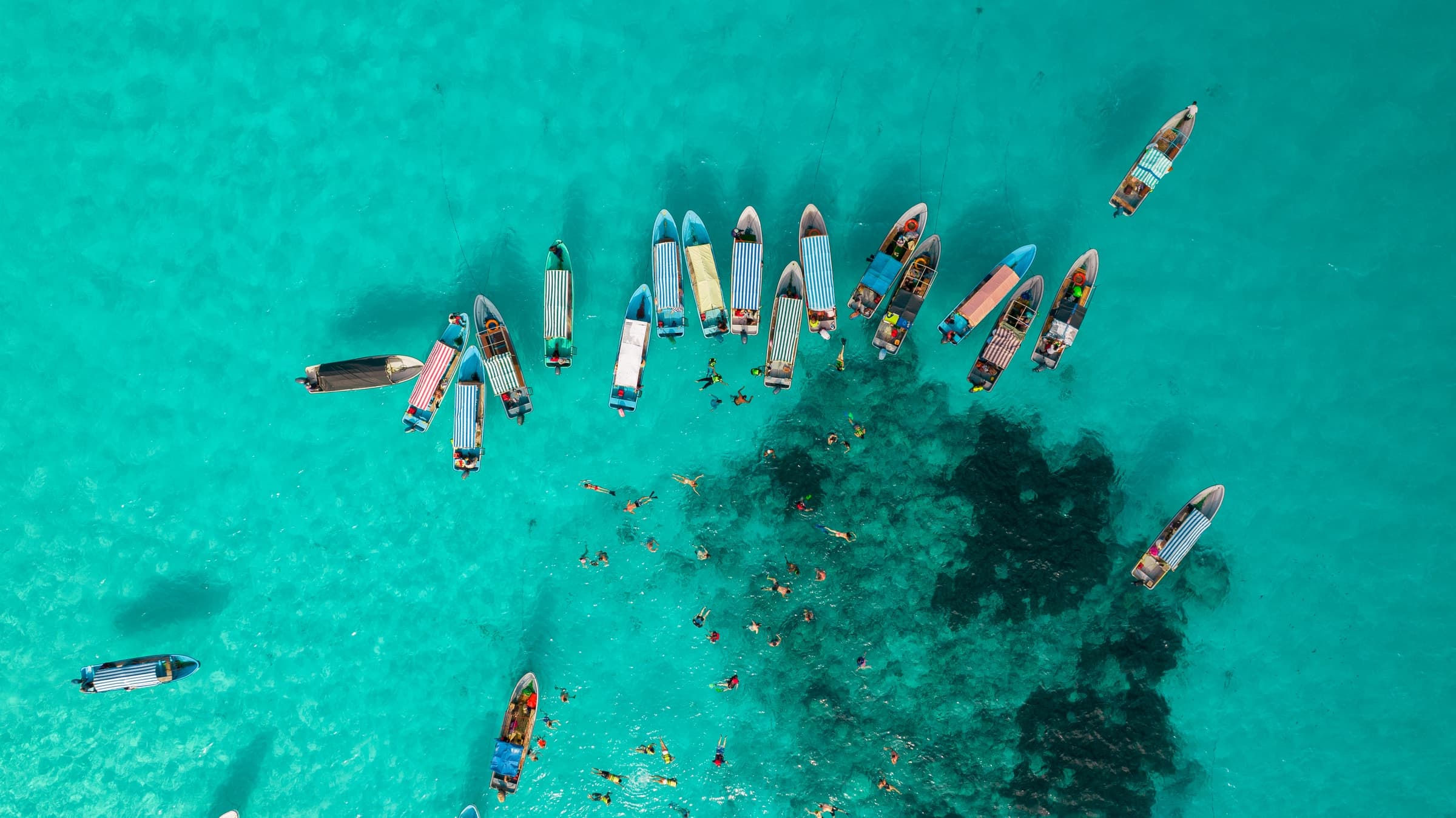 Aerial view of boats and snorkellers over a coral reef