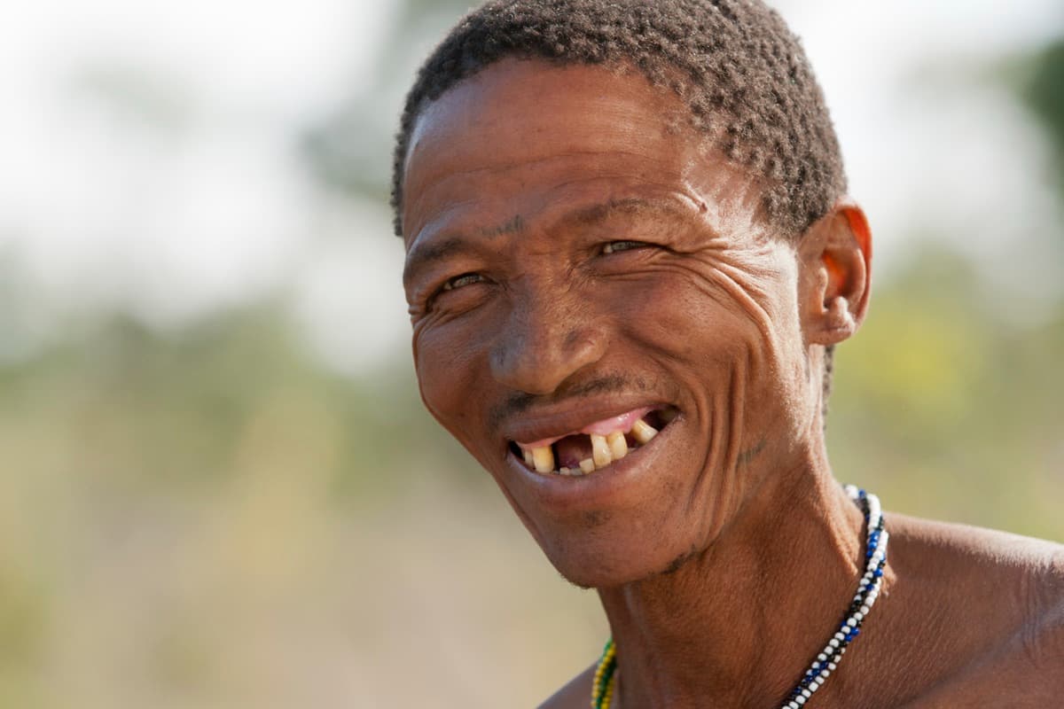 A smiling man wearing beaded necklaces in the Kalahari
