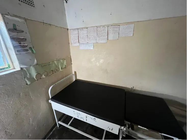 A maternity bed in Mucheni Clinic, with handwritten emergency instructions on the wall above it